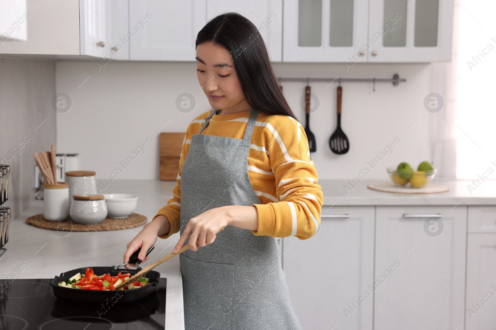 Photo of Beautiful woman cooking vegetable dish in kitchen. Space for text