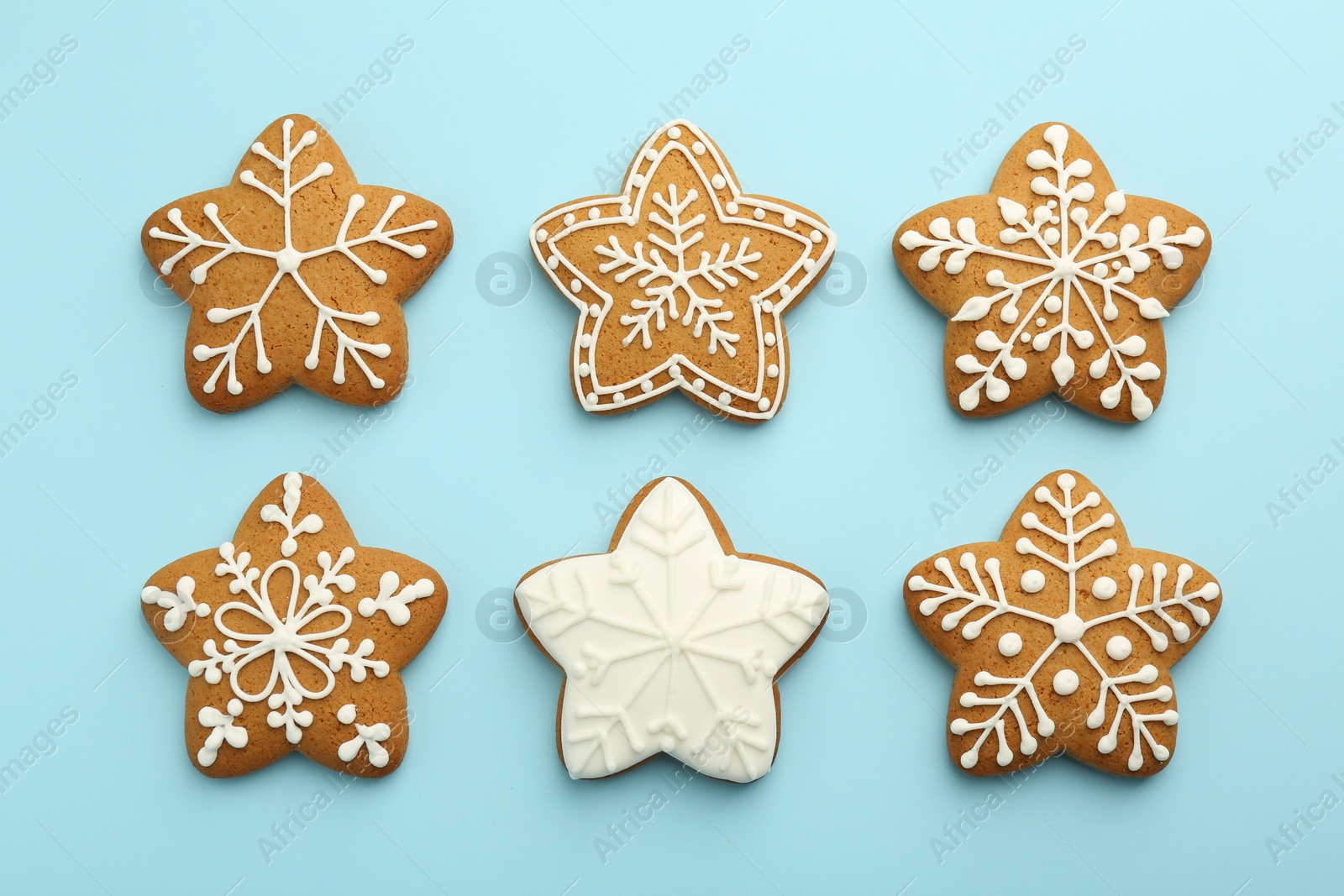 Photo of Tasty star shaped Christmas cookies with icing on light blue background, flat lay