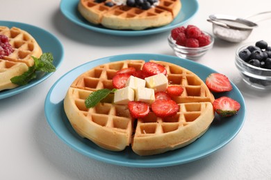 Photo of Tasty Belgian waffles with fresh berries served on white table, closeup