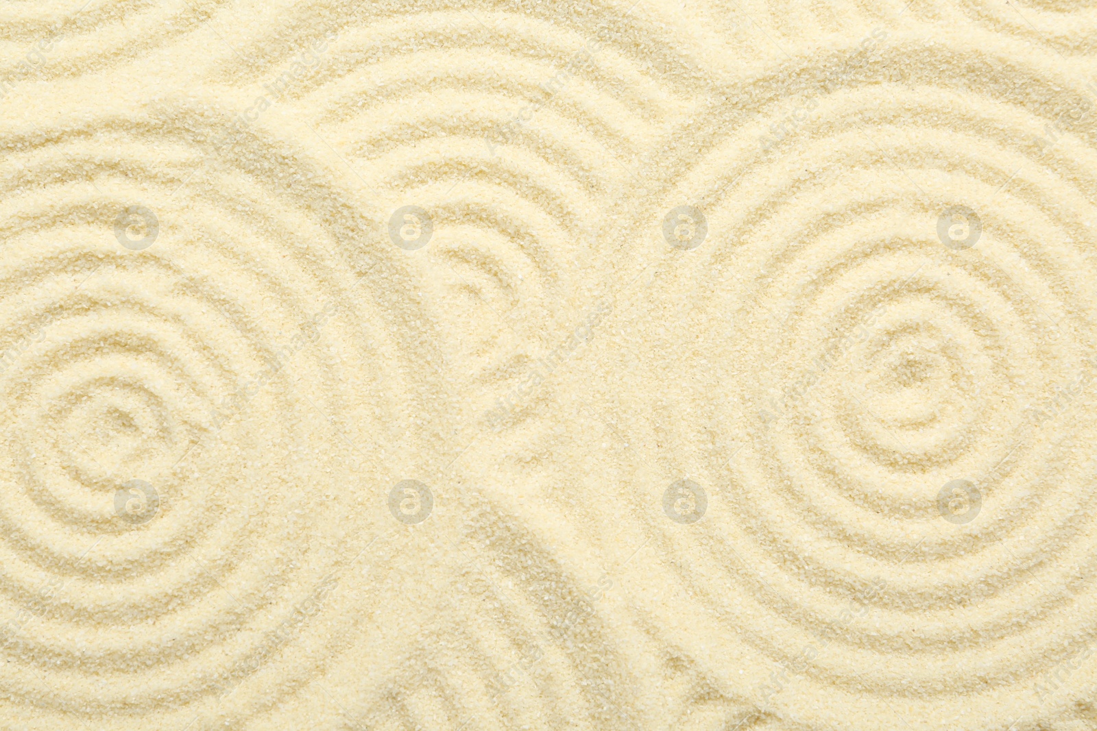 Photo of Zen rock garden. Circle patterns on beige sand, top view