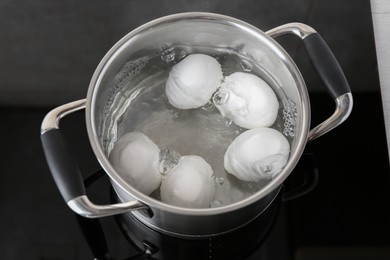 Chicken eggs boiling in pot on electric stove, above view