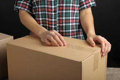 Photo of Woman packing box at table, closeup. Space for design