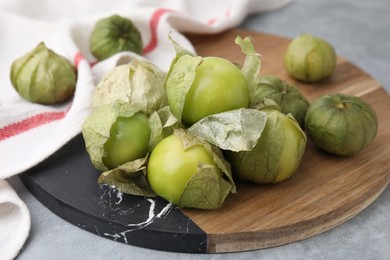 Photo of Fresh green tomatillos with husk on gray table, closeup