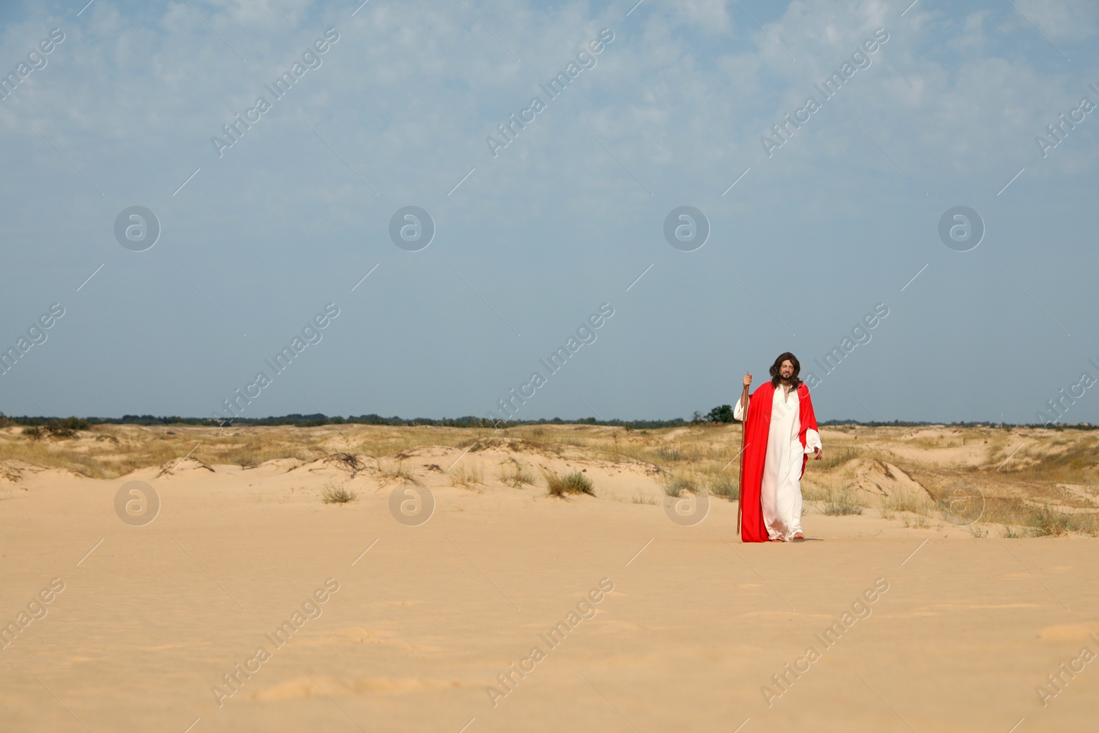 Photo of Jesus Christ walking with stick in desert. Space for text