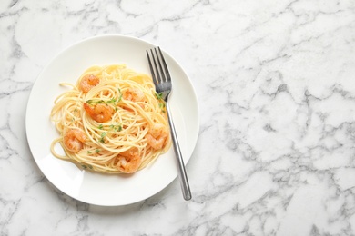 Plate with spaghetti and shrimps on light background, top view