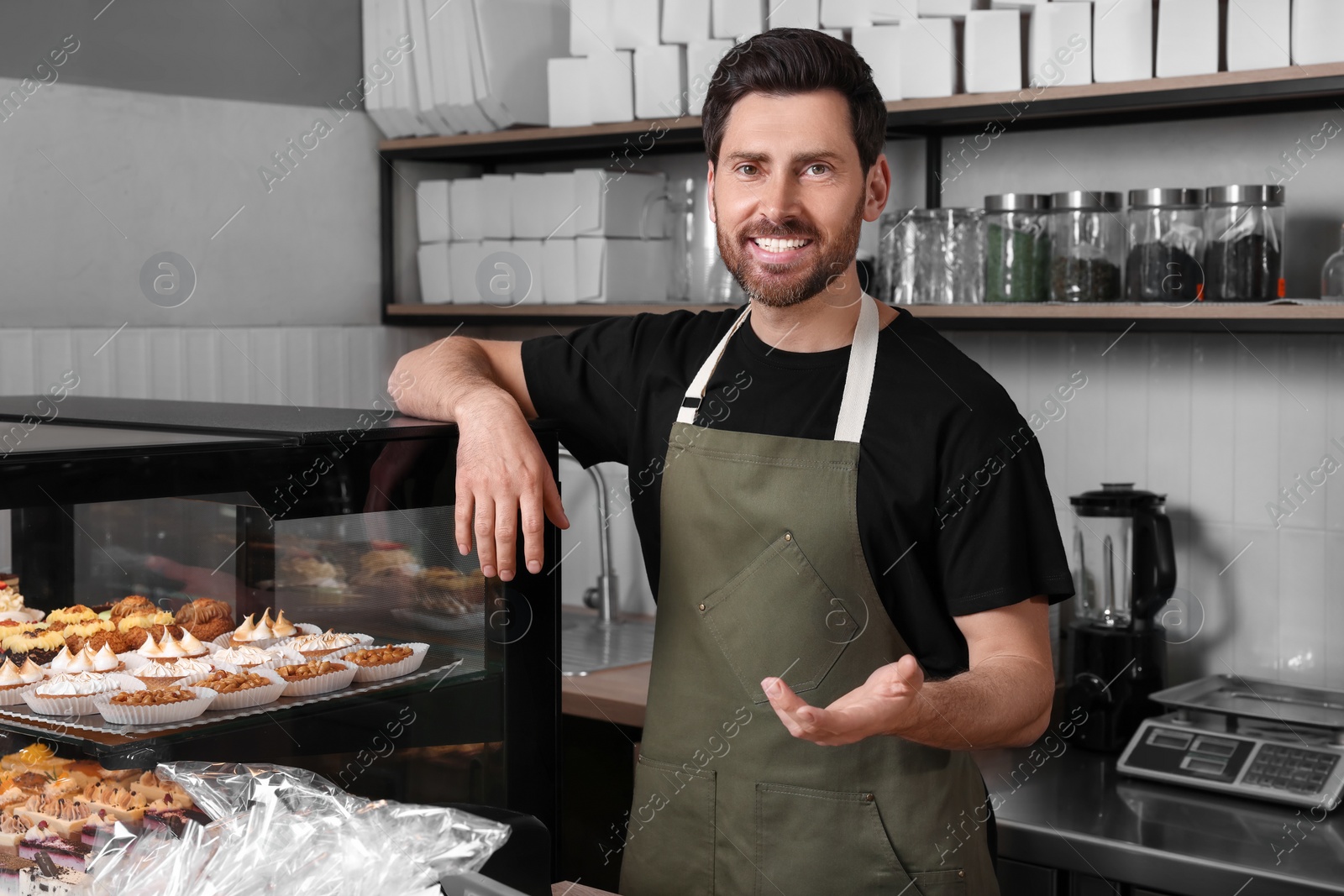 Photo of Portrait of happy seller near showcase in bakery shop