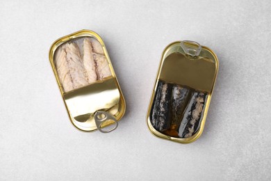 Open tin cans with mackerel fillets on grey table, flat lay
