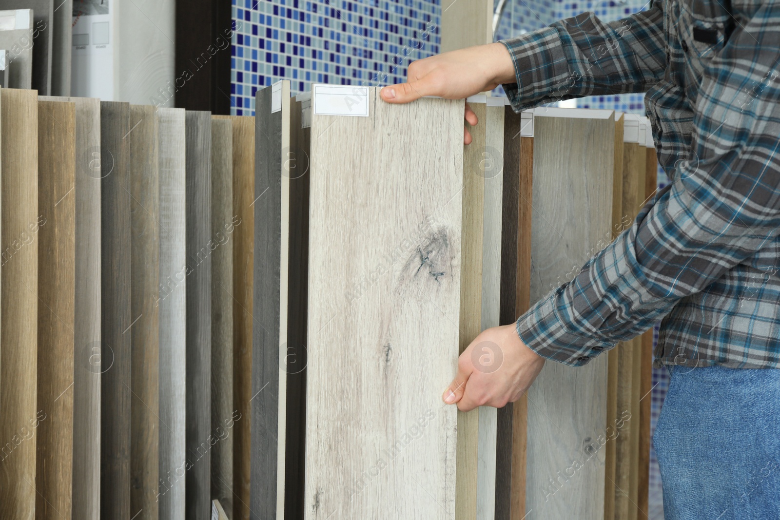 Photo of Man choosing tile among different samples in store, closeup