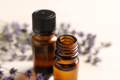 Photo of Essential oil and lavender flowers on white table, closeup