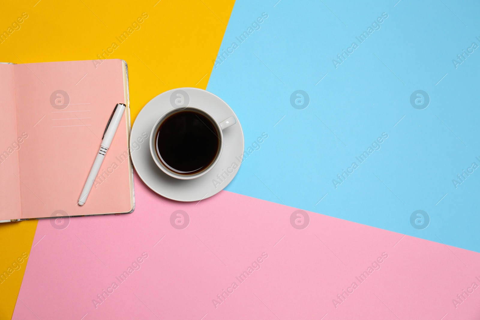 Photo of Cup of coffee and notebook with pen on color background, top view. Space for text