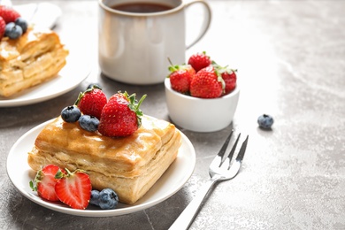 Fresh delicious puff pastry with sweet berries on grey marble table. Space for text