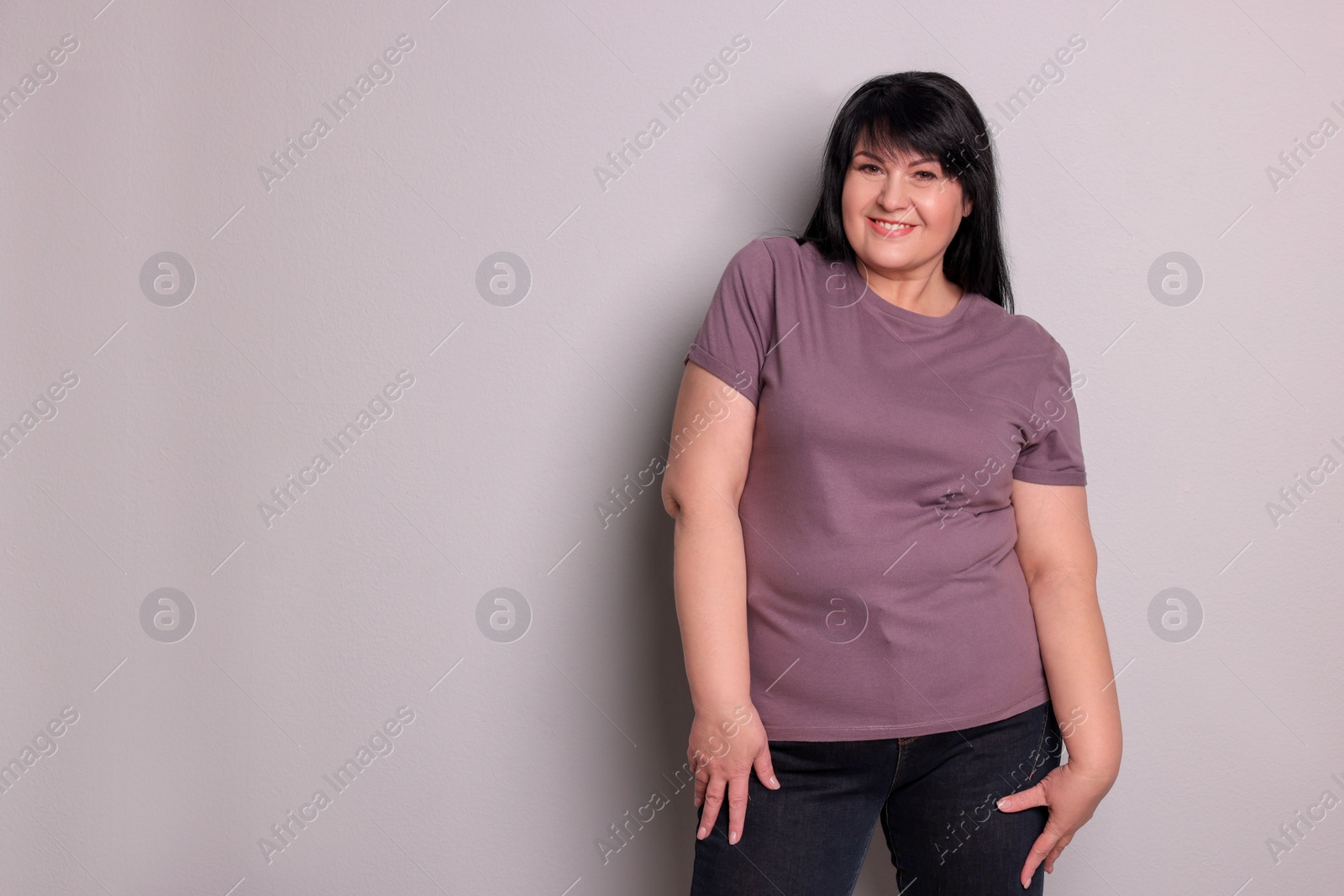 Photo of Beautiful overweight mature woman with charming smile on light grey background. Space for text