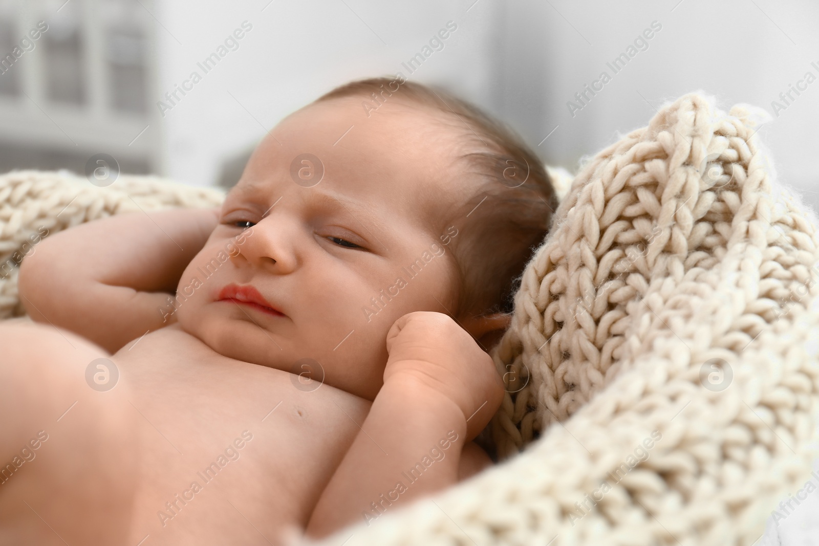 Photo of Cute little baby sleeping on knitted plaid in cradle