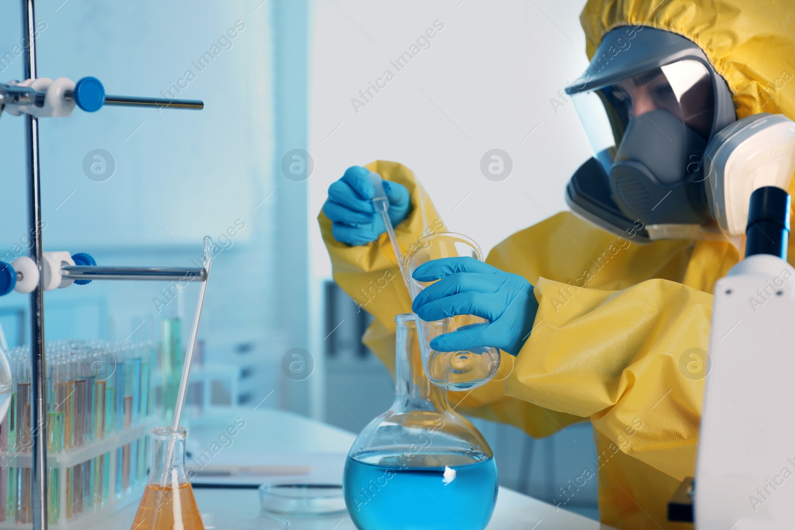 Photo of Scientist in chemical protective suit working at laboratory, focus on hands. Virus research