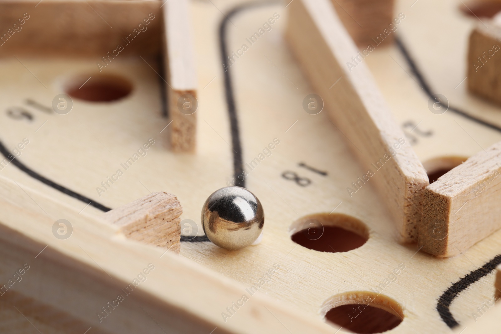 Photo of Wooden toy maze with metal ball, closeup