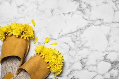 Photo of Beautiful slippers and chrysanthemum flowers on white marble background, flat lay. Space for text