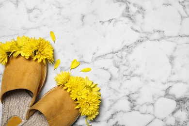 Beautiful slippers and chrysanthemum flowers on white marble background, flat lay. Space for text