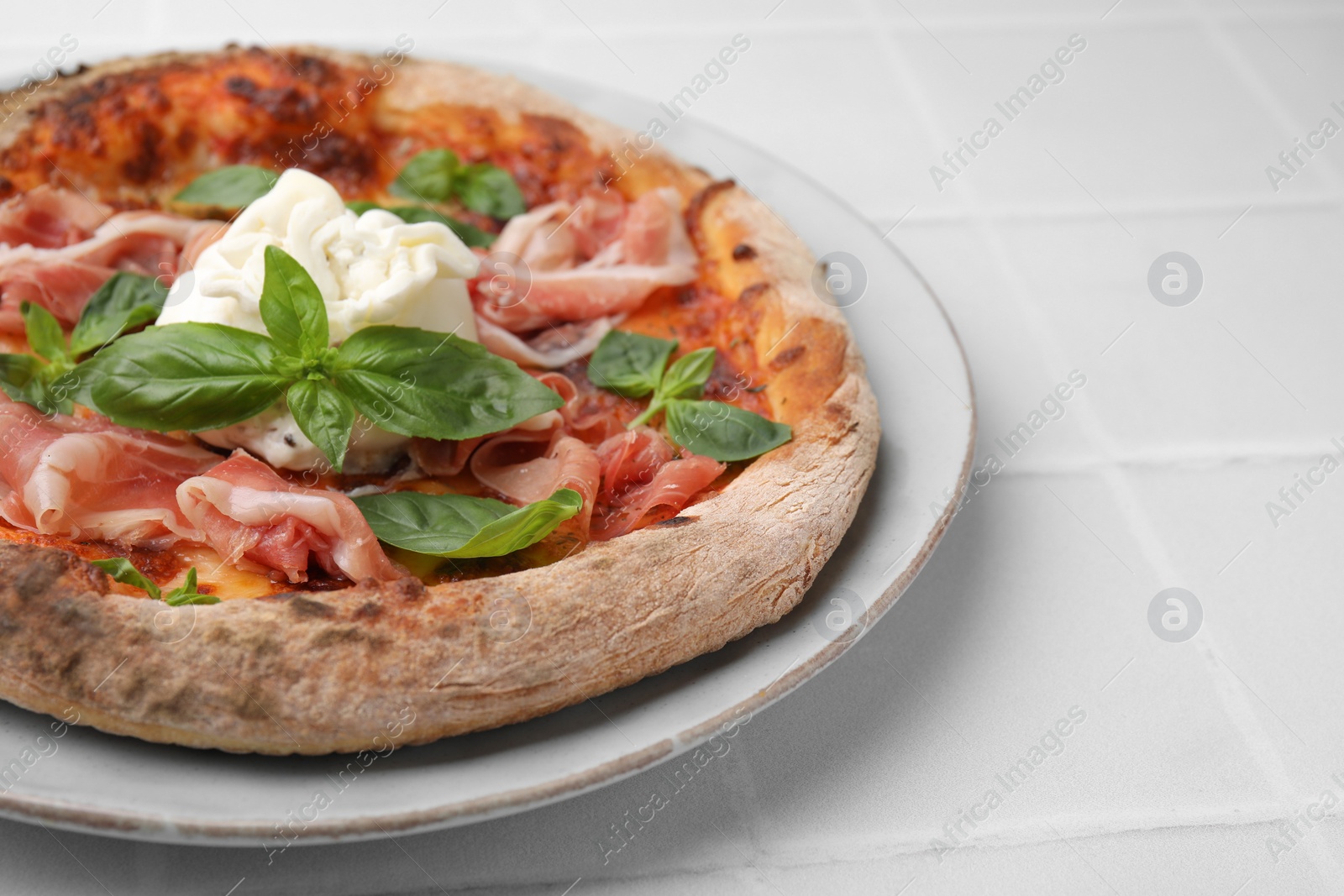 Photo of Delicious pizza with burrata cheese, basil and ham on white table, closeup. Space for text