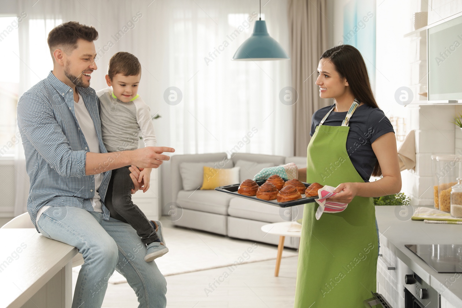 Photo of Woman treating family with oven baked buns in kitchen