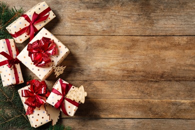 Photo of Christmas gift boxes with red bows on wooden background, flat lay. Space for text