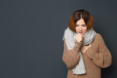Woman suffering from cough on dark background. Space for text