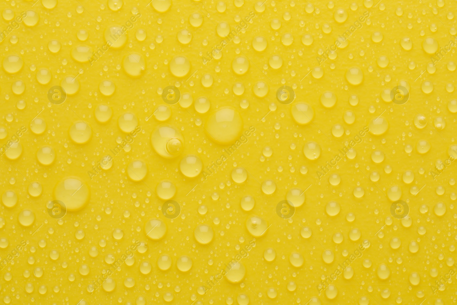 Photo of Water drops on yellow background, top view