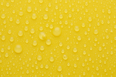 Water drops on yellow background, top view