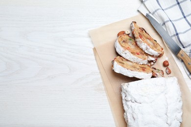 Traditional Christmas Stollen with icing sugar on white wooden table, flat lay. Space for text