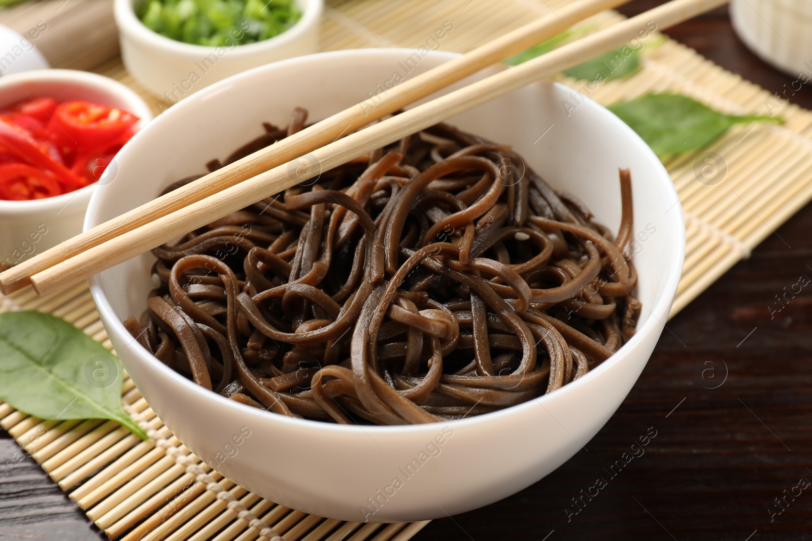 Photo of Tasty buckwheat noodles (soba) served on wooden table, closeup