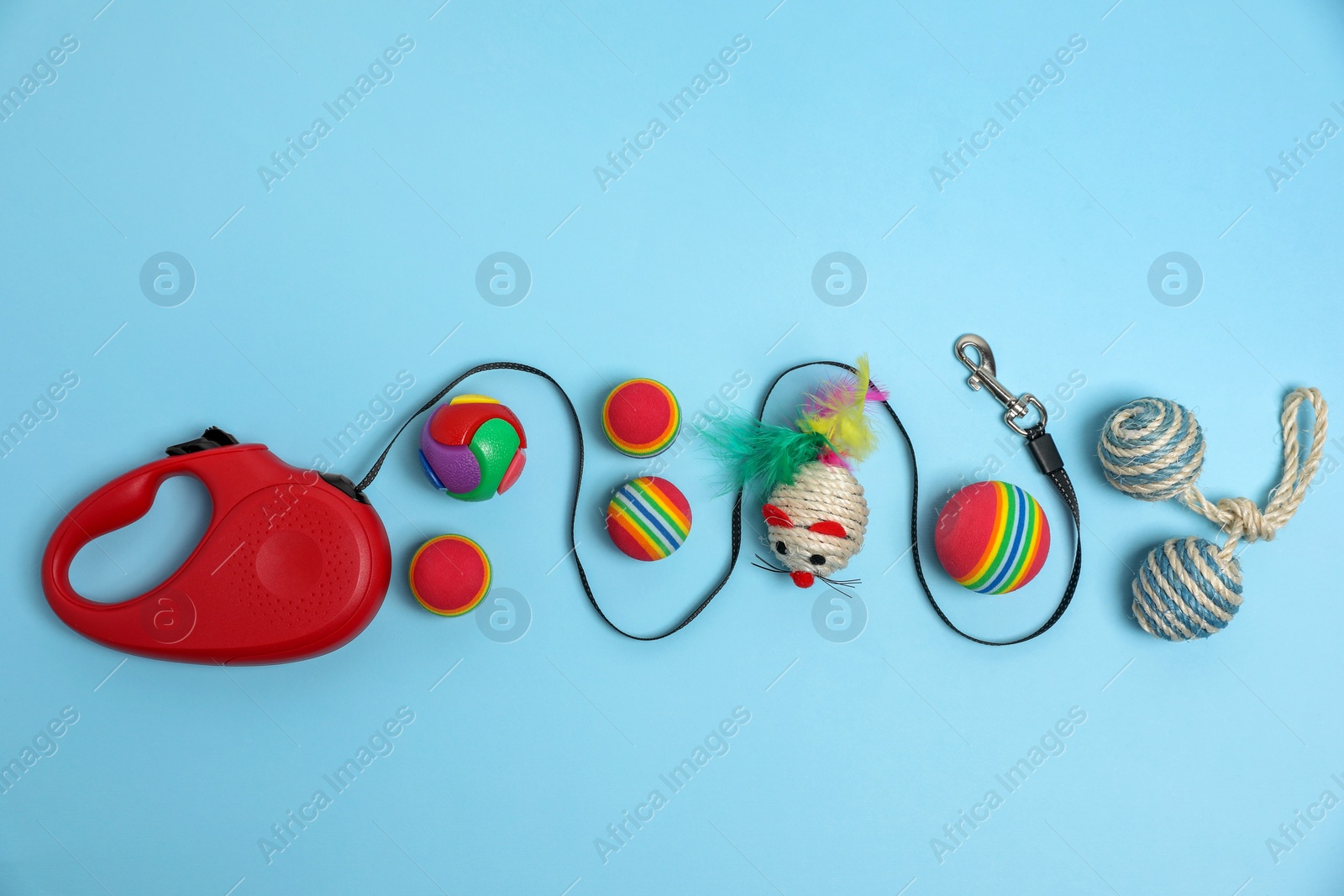 Photo of Flat lay composition with red pet retractable leash and toys on light blue background