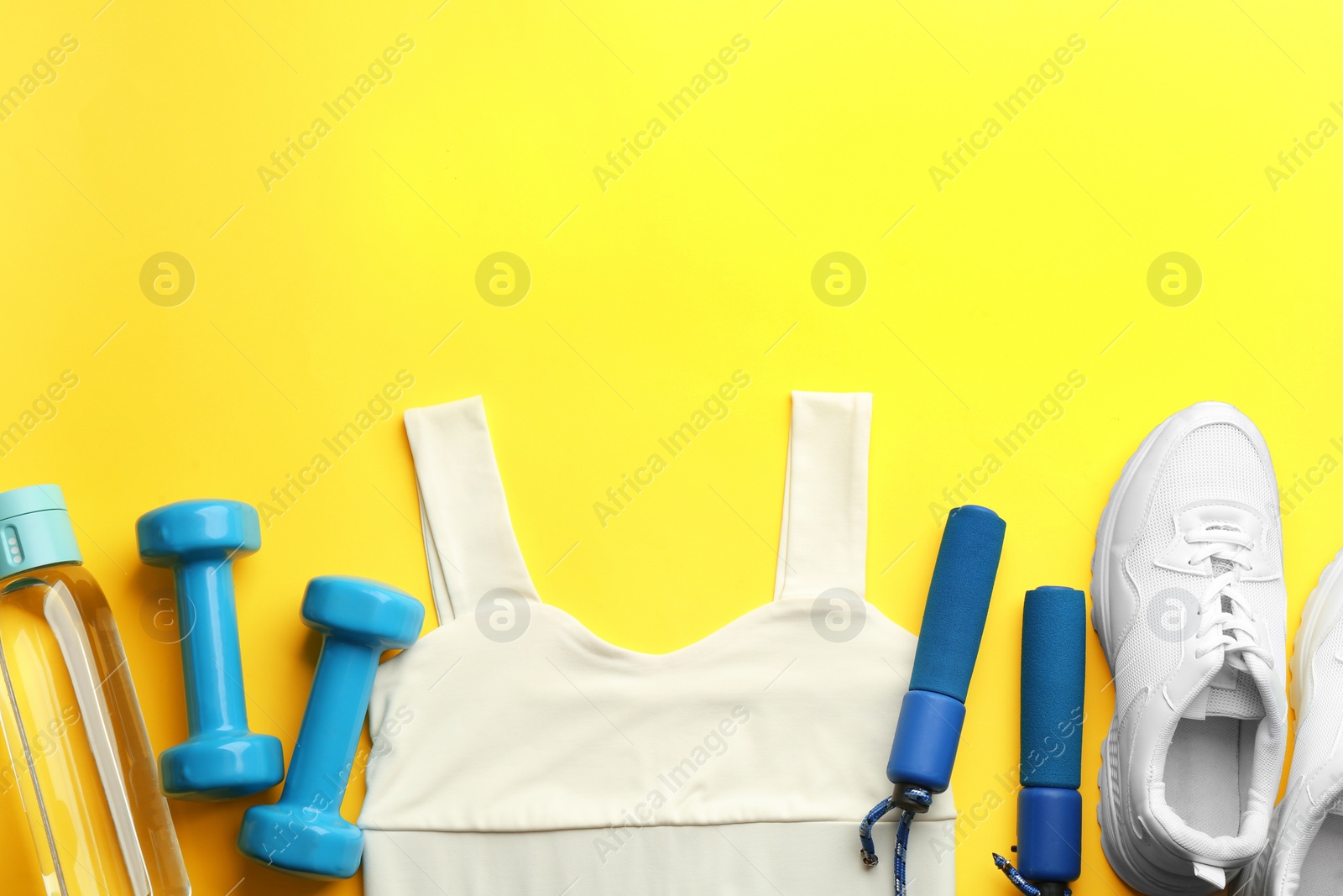 Photo of Flat lay composition with sportswear and equipment on yellow background, space for text. Gym workout