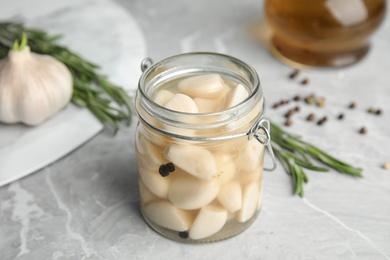 Photo of Composition with jar of pickled garlic on marble table