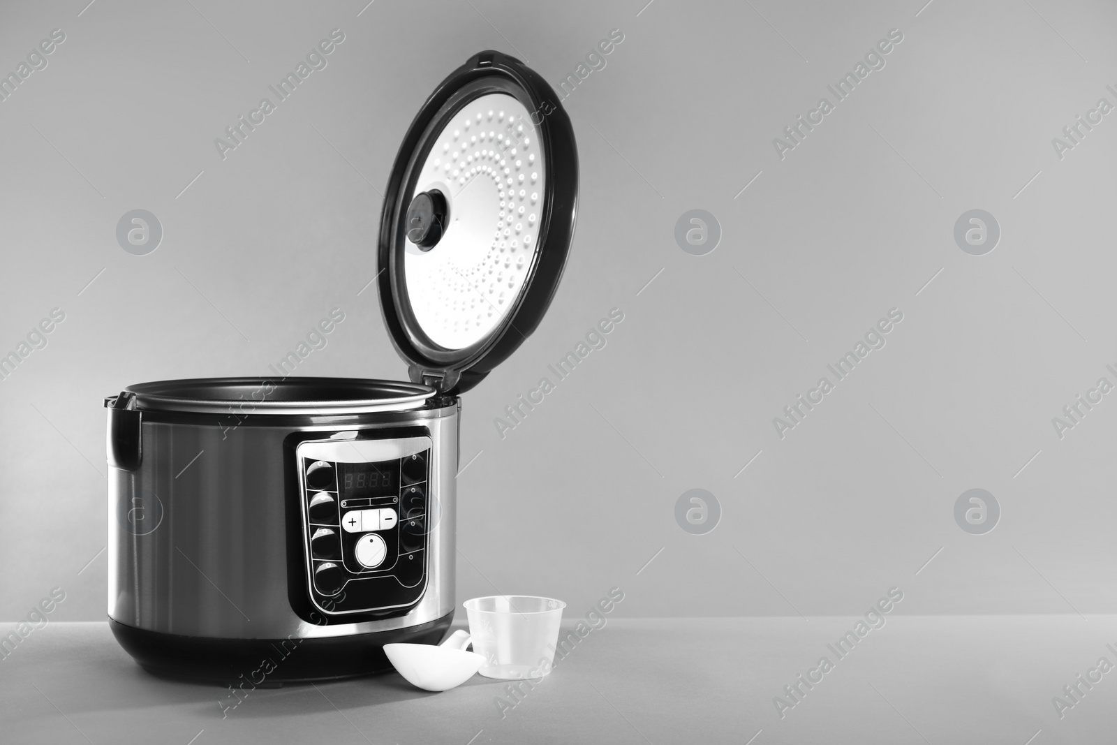 Photo of Modern powerful multi cooker on table against grey background. Space for text