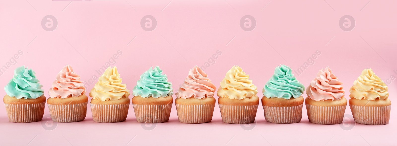 Photo of Row of delicious cupcakes on color background, space for text