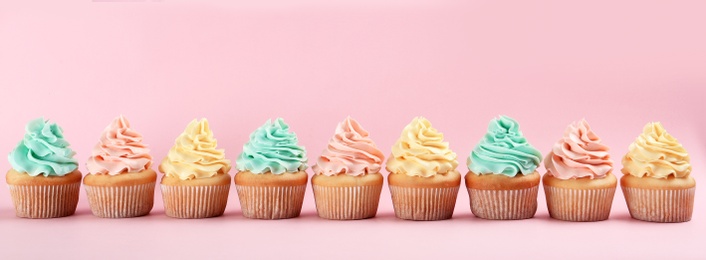 Photo of Row of delicious cupcakes on color background, space for text