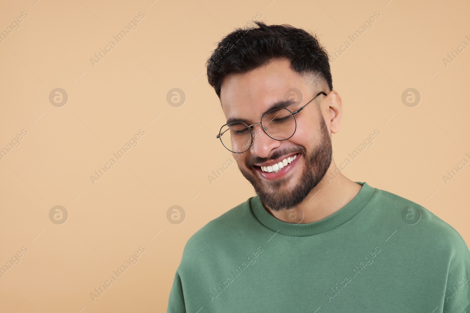 Photo of Handsome young man laughing on beige background, space for text