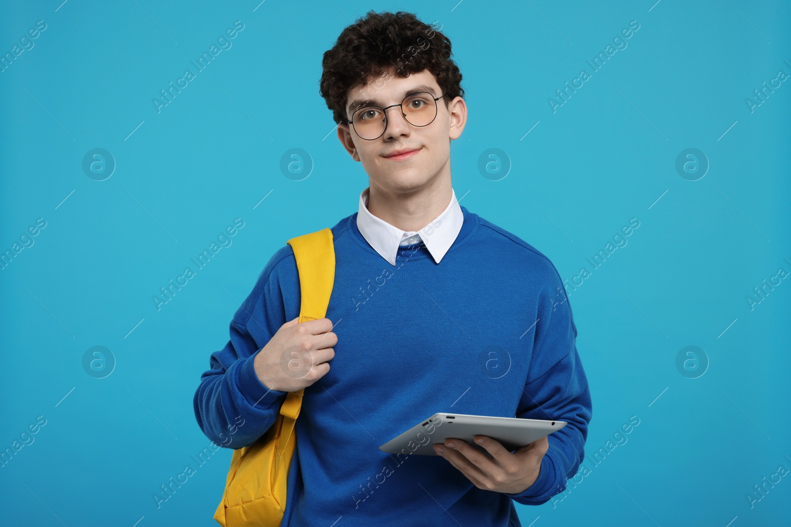 Photo of Portrait of student with backpack and tablet on light blue background