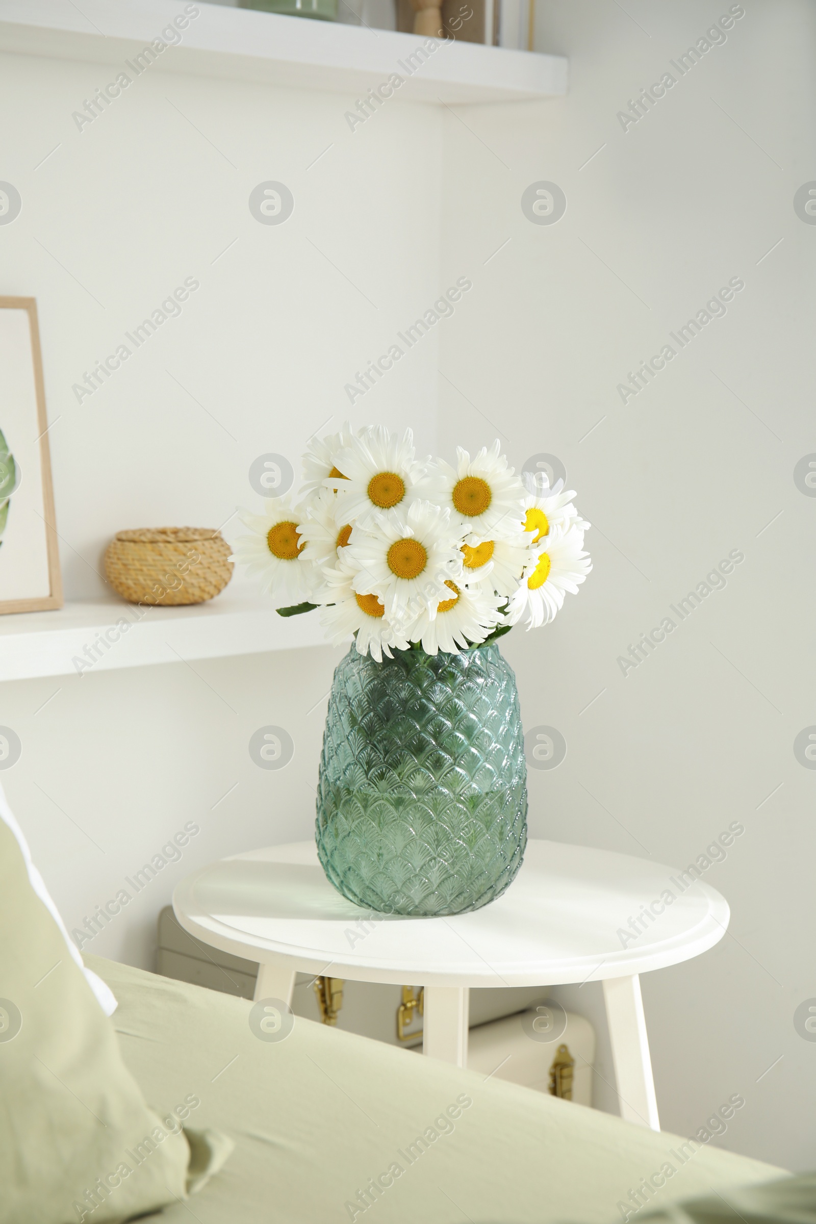 Photo of Bouquet of beautiful daisy flowers on table in bedroom