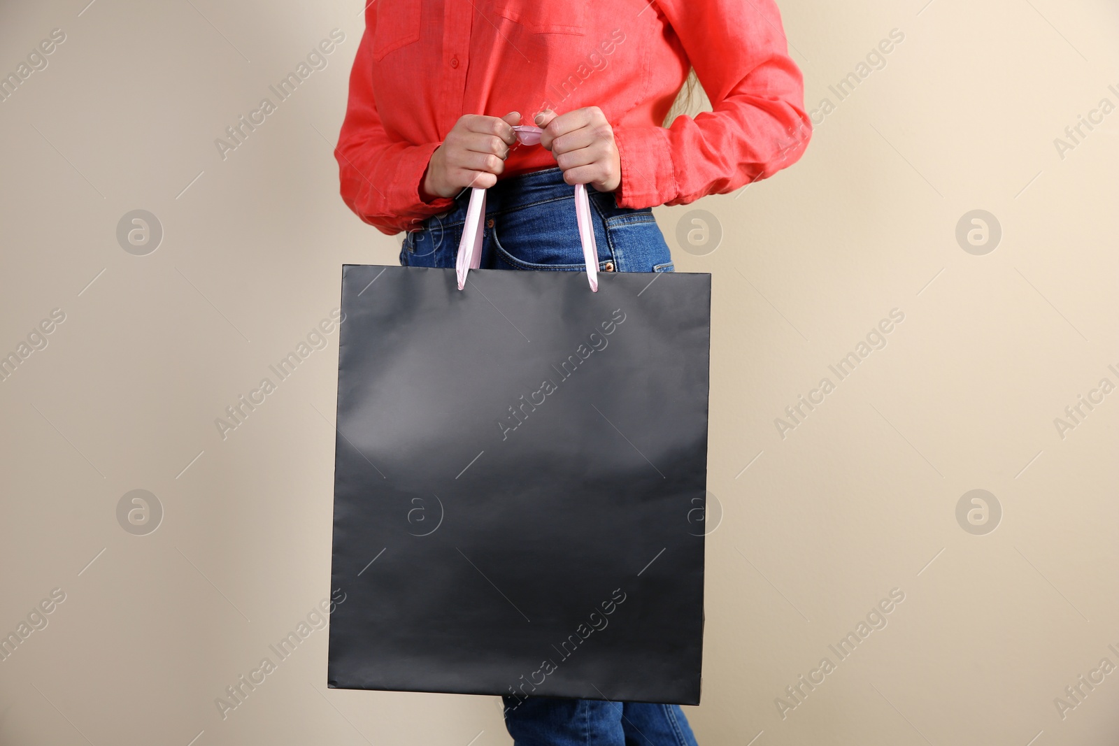 Photo of Woman holding paper shopping bag on color background. Mock up for design