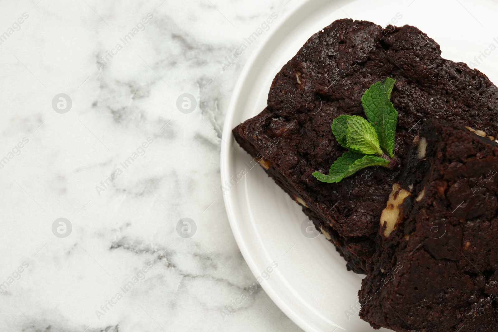 Photo of Delicious brownies with nuts and mint on white marble table, top view. Space for text