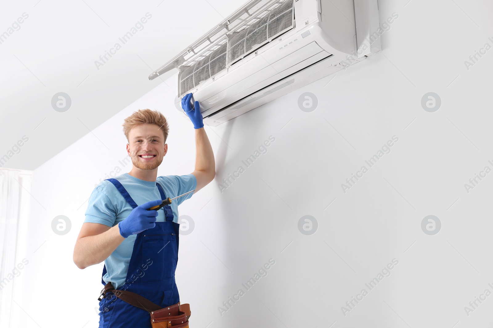 Photo of Professional technician maintaining modern air conditioner indoors