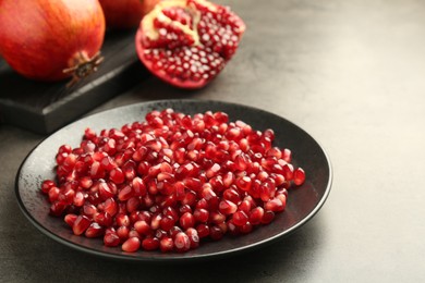 Photo of Ripe juicy pomegranate grains on grey table