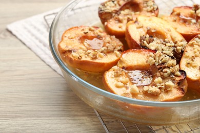 Photo of Delicious baked quinces with nuts and honey in bowl on wooden table, closeup