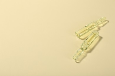 Glass ampoules with liquid on beige background. Space for text