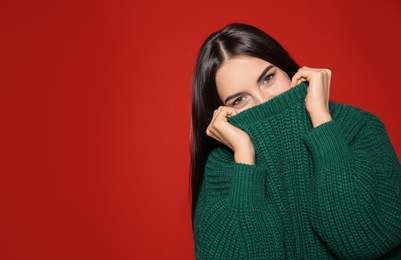 Image of Pretty woman wearing warm sweater on red background. Space for text