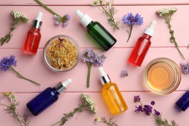 Aromatherapy. Different essential oils and flowers on pink wooden table, flat lay