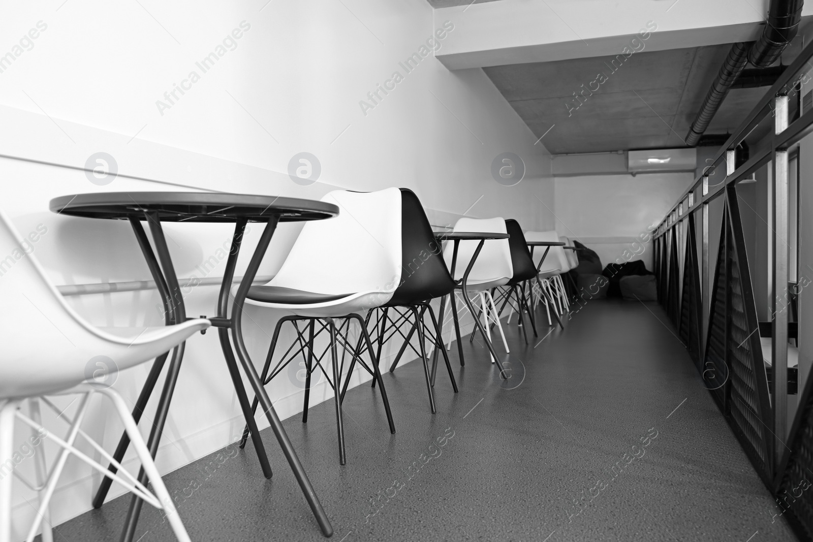 Photo of Hostel dining room interior with tables and chairs along white wall