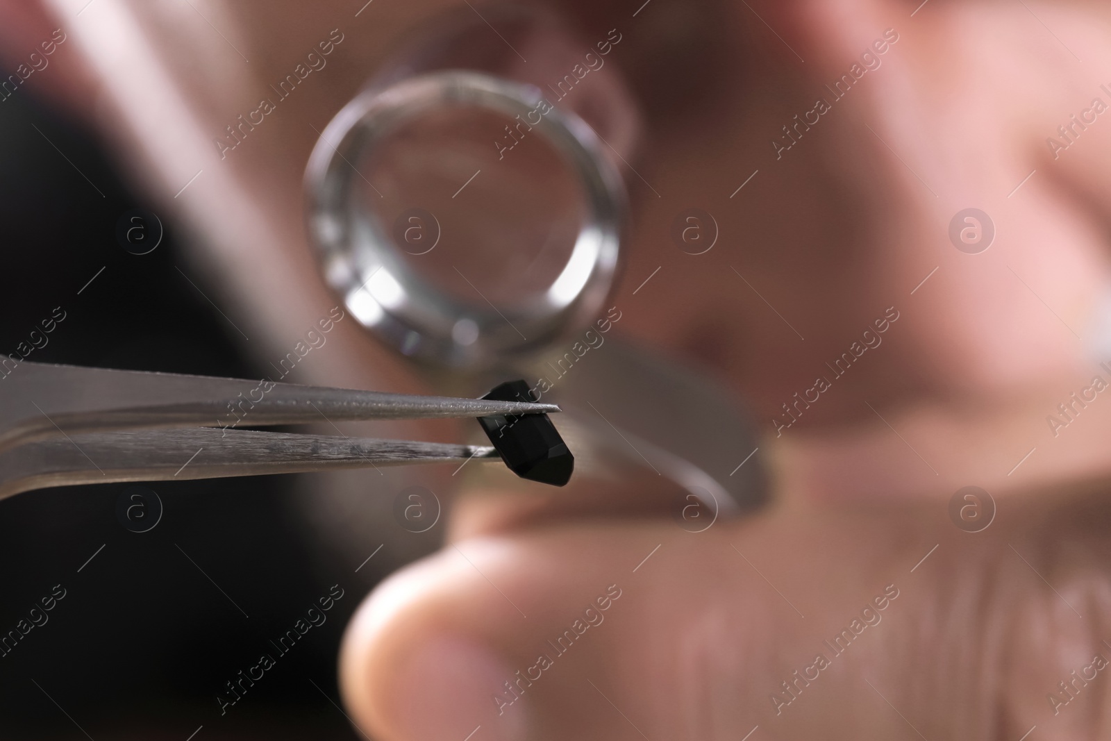 Photo of Male jeweler examining precious stone in workshop, closeup view