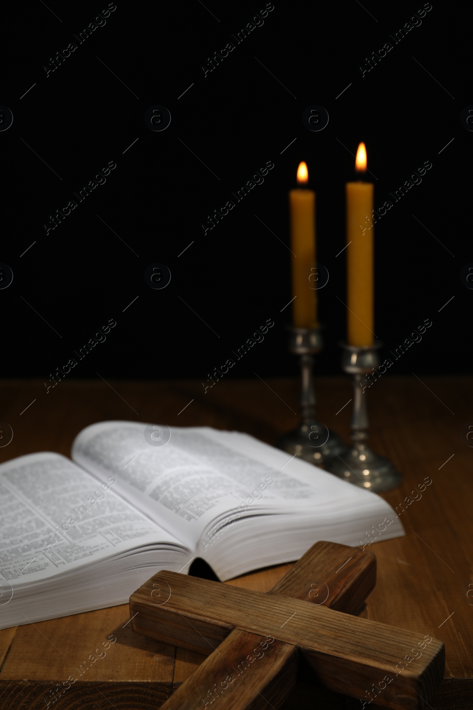 Photo of Bible, cross and church candles on wooden table