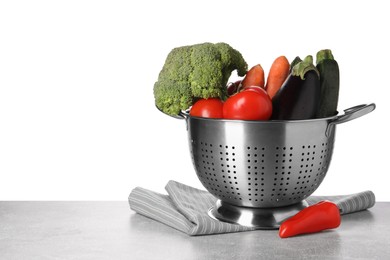 Photo of Different fresh vegetables in colander and napkin on table against white background. Space for text